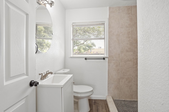 bathroom featuring vanity, toilet, wood-type flooring, and tiled shower