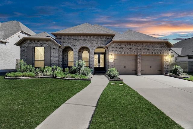 french country inspired facade featuring a lawn, a garage, and french doors