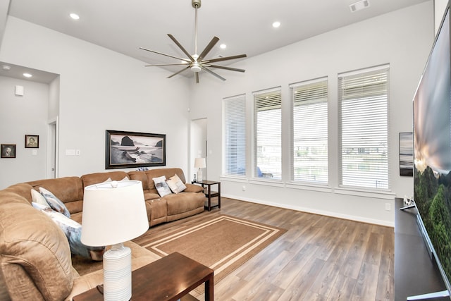 living room featuring wood-type flooring, ceiling fan, and a high ceiling