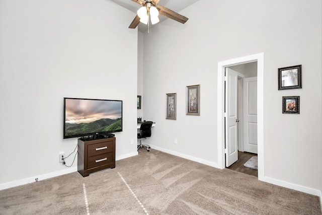 carpeted living room featuring ceiling fan and a high ceiling