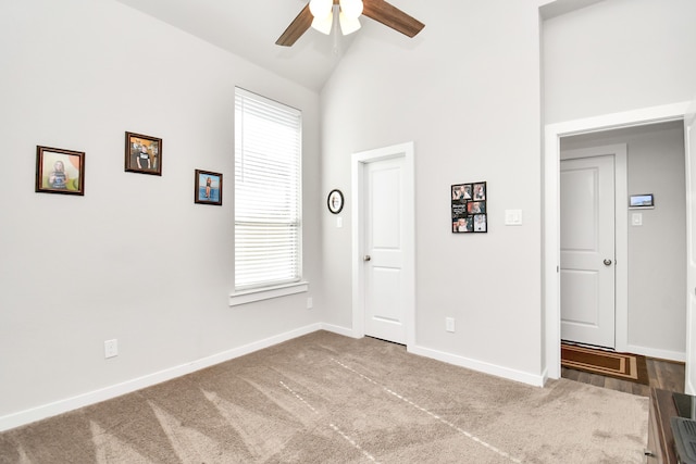 empty room featuring carpet flooring, ceiling fan, high vaulted ceiling, and a healthy amount of sunlight