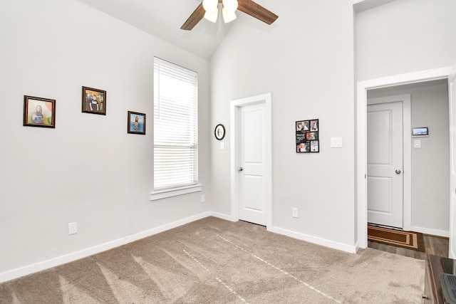 empty room with ceiling fan, a healthy amount of sunlight, high vaulted ceiling, and carpet