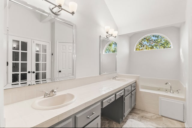 bathroom with vanity, a relaxing tiled tub, and lofted ceiling