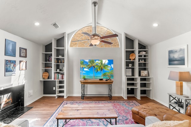 living room featuring a premium fireplace, ceiling fan, lofted ceiling with beams, and wood-type flooring