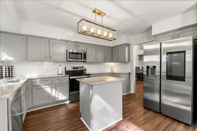 kitchen featuring pendant lighting, dark wood-type flooring, gray cabinets, a kitchen island, and stainless steel appliances