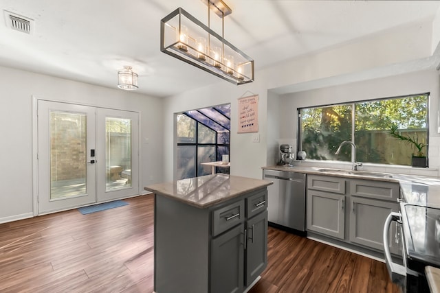 kitchen with gray cabinetry, a center island, stainless steel dishwasher, dark hardwood / wood-style floors, and decorative light fixtures