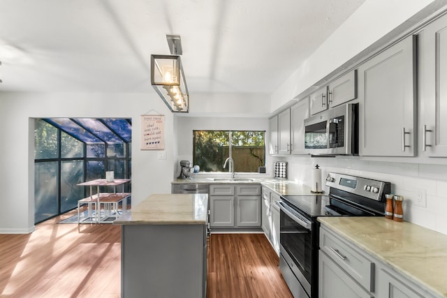 kitchen featuring decorative backsplash, appliances with stainless steel finishes, gray cabinetry, dark hardwood / wood-style floors, and hanging light fixtures