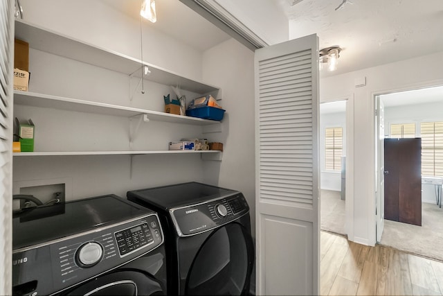 washroom with washer and dryer and light wood-type flooring