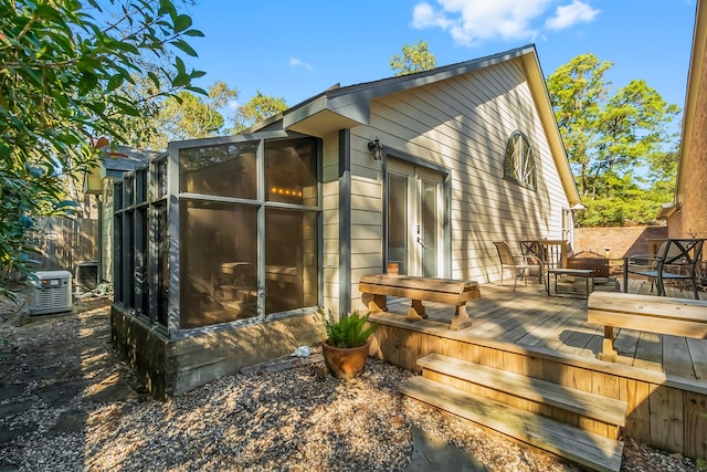 view of home's exterior with a sunroom and a wooden deck