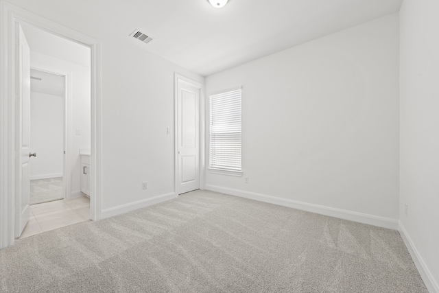 unfurnished room with baseboards, visible vents, and light carpet