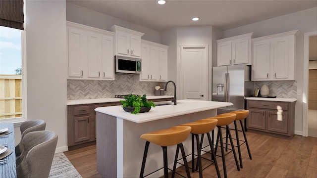 kitchen with a kitchen breakfast bar, tasteful backsplash, light countertops, recessed lighting, and stainless steel fridge
