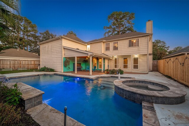 pool at dusk featuring an in ground hot tub