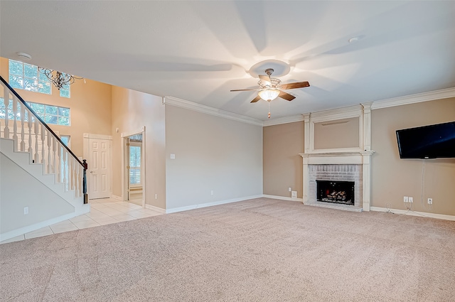 unfurnished living room with light colored carpet, a brick fireplace, ceiling fan, and crown molding