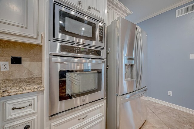 kitchen featuring crown molding, appliances with stainless steel finishes, tasteful backsplash, light tile patterned flooring, and white cabinetry