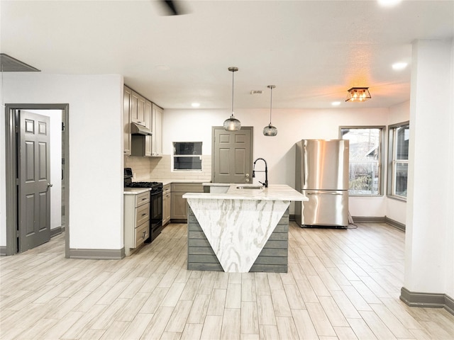 kitchen featuring sink, gray cabinets, black stove, stainless steel fridge, and a kitchen island with sink