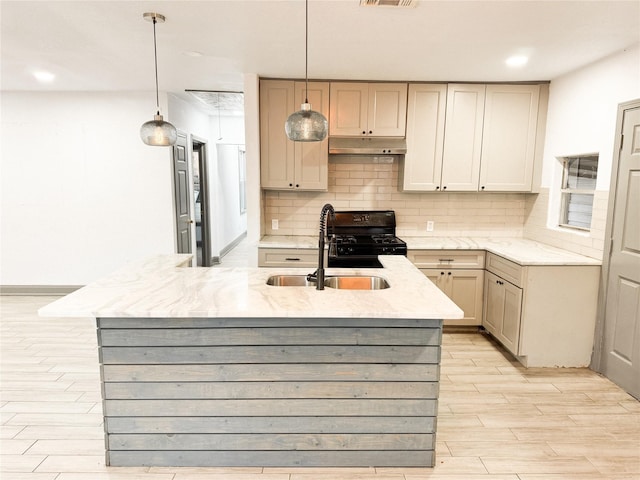 kitchen featuring a kitchen island with sink, black range, pendant lighting, sink, and tasteful backsplash