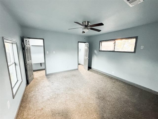 unfurnished bedroom with ceiling fan, light carpet, and multiple windows