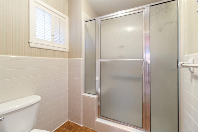 bathroom featuring toilet, an enclosed shower, parquet flooring, and tile walls