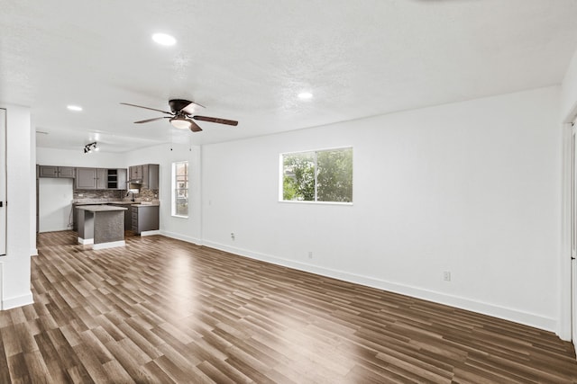 unfurnished living room featuring a textured ceiling, ceiling fan, dark hardwood / wood-style flooring, and sink