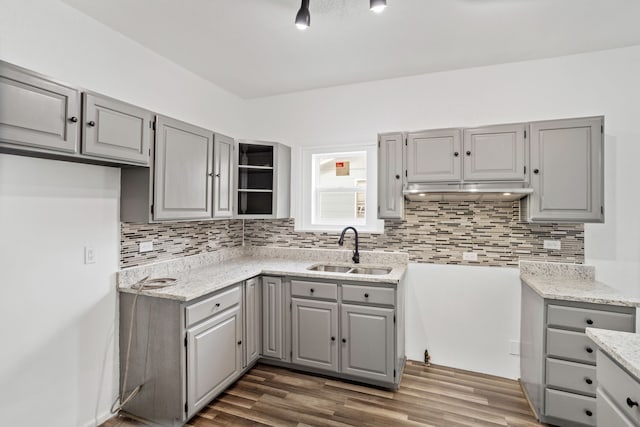 kitchen with tasteful backsplash, light stone counters, sink, and dark wood-type flooring