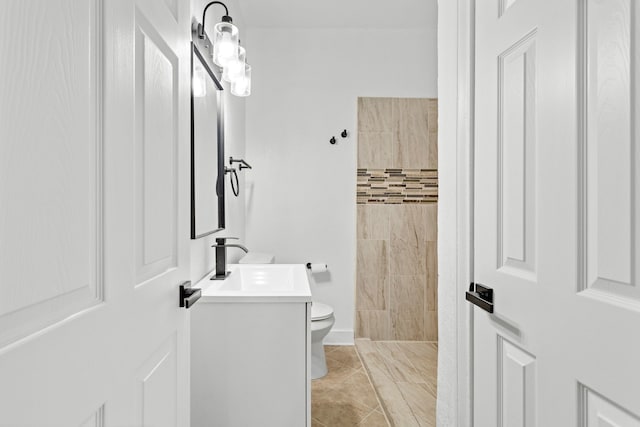 bathroom with tile patterned flooring, vanity, toilet, and tiled shower