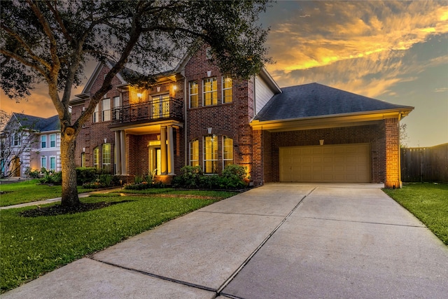 view of front of home with a garage, a balcony, and a yard