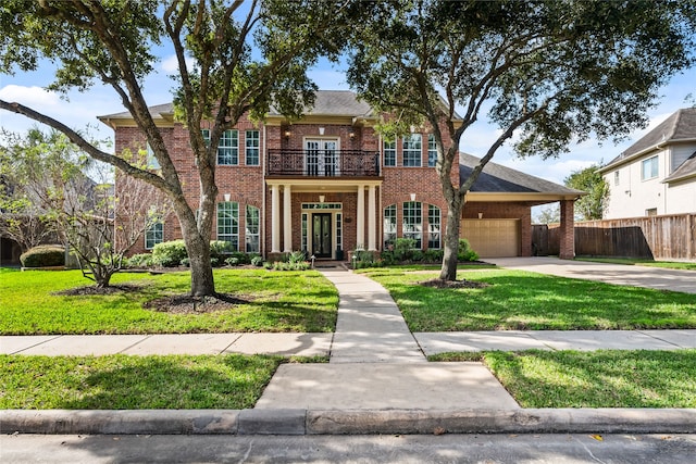 colonial inspired home with a garage, a balcony, a front yard, and french doors