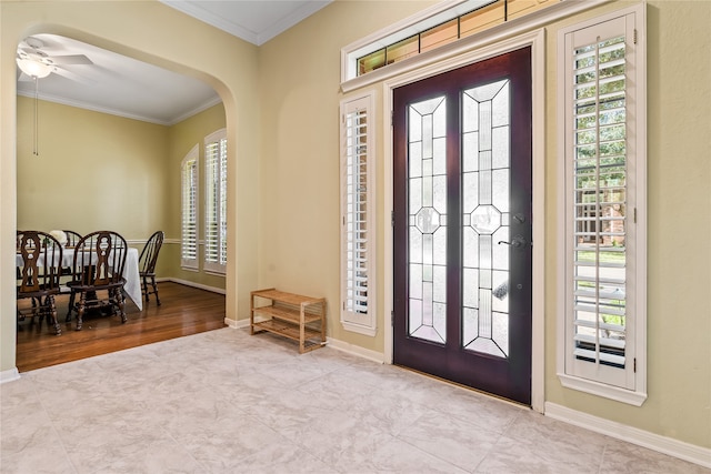 foyer entrance featuring a wealth of natural light, crown molding, ceiling fan, and light hardwood / wood-style flooring