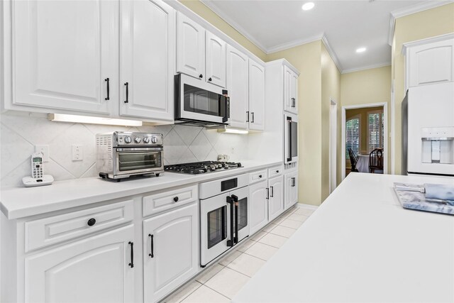 kitchen with french doors, stainless steel appliances, crown molding, light tile patterned floors, and white cabinetry