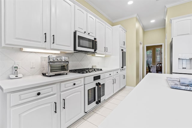 kitchen with light tile patterned flooring, white appliances, white cabinetry, light countertops, and ornamental molding