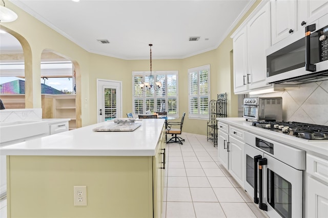 kitchen featuring stainless steel gas stovetop, white cabinetry, light countertops, and a center island