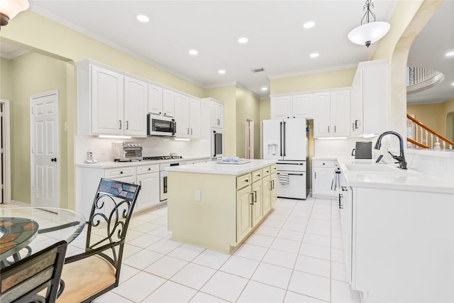 kitchen featuring appliances with stainless steel finishes, sink, white cabinets, a center island, and hanging light fixtures