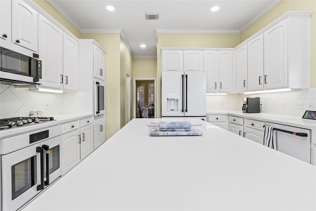 kitchen featuring appliances with stainless steel finishes, tasteful backsplash, white cabinetry, and crown molding