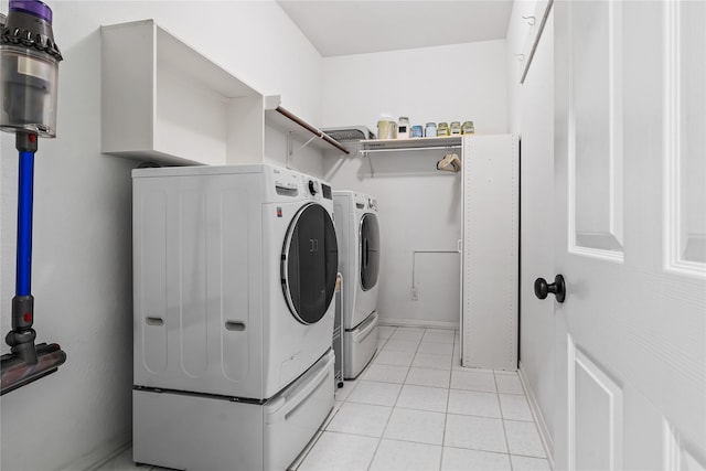 clothes washing area with laundry area, separate washer and dryer, light tile patterned flooring, and baseboards