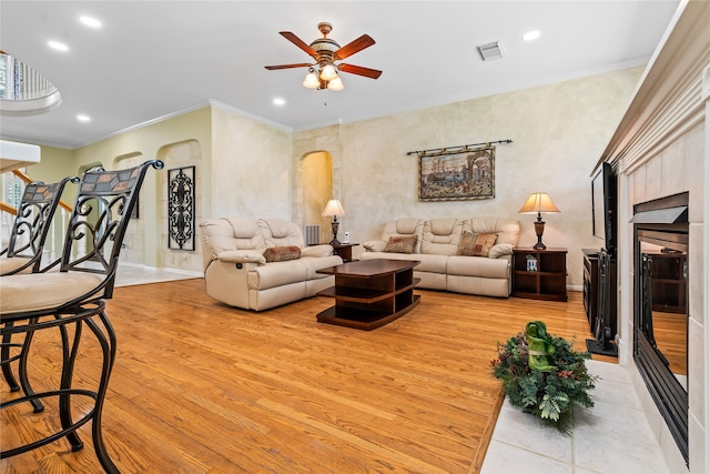 living room featuring light hardwood / wood-style flooring, ceiling fan, and ornamental molding