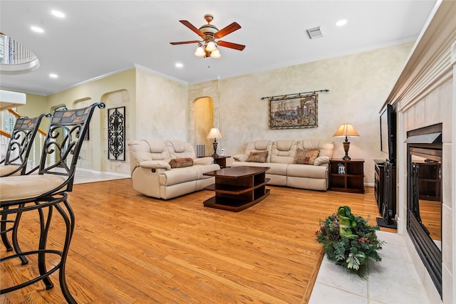 living room featuring visible vents, arched walkways, light wood-style flooring, crown molding, and recessed lighting