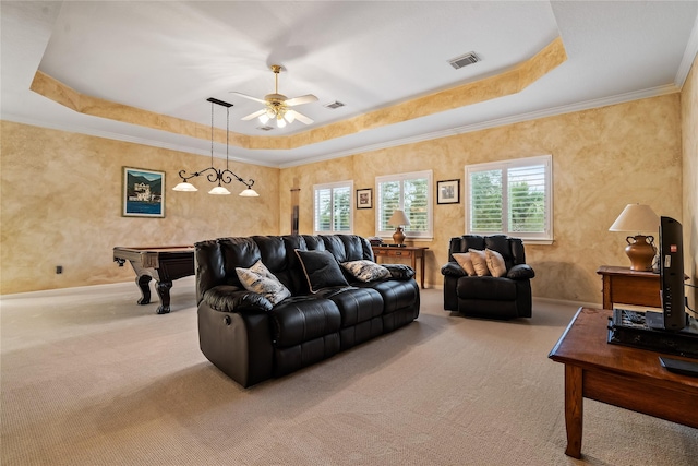 carpeted living area with ceiling fan, visible vents, a raised ceiling, and ornamental molding