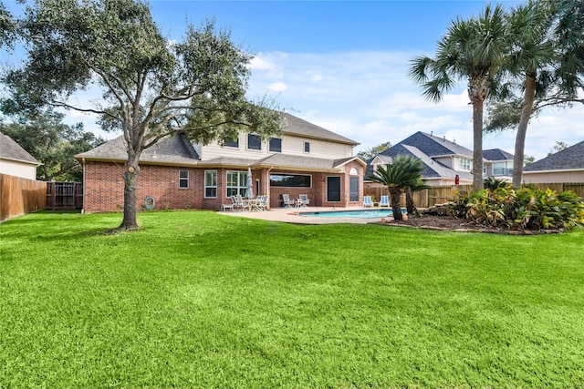 rear view of house with a fenced in pool, a patio area, and a lawn