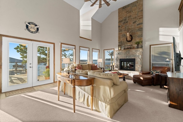 172 Little Dove, Livingston, TX 77351 - living area featuring a ceiling fan, french doors, high vaulted ceiling, a stone fireplace, and light carpet