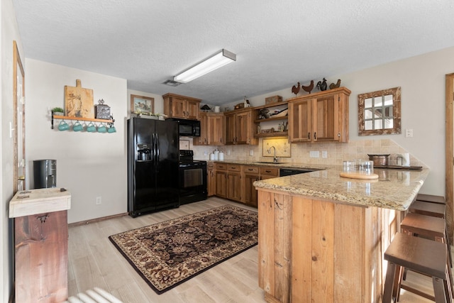 172 Little Dove, Livingston, TX 77351 - kitchen with black appliances, a sink, a peninsula, open shelves, and light wood finished floors