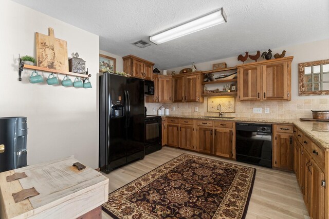 kitchen with black appliances, decorative backsplash, light hardwood / wood-style floors, and sink