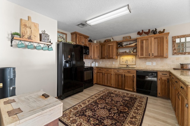 172 Little Dove, Livingston, TX 77351 - kitchen featuring black appliances, a sink, open shelves, light wood-type flooring, and brown cabinets