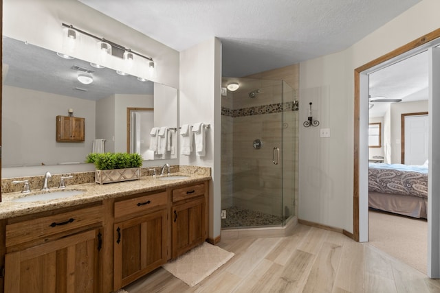 bathroom featuring vanity, hardwood / wood-style flooring, ceiling fan, a textured ceiling, and an enclosed shower