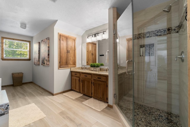 172 Little Dove, Livingston, TX 77351 - bathroom with double vanity, a stall shower, wood finished floors, baseboards, and a textured ceiling