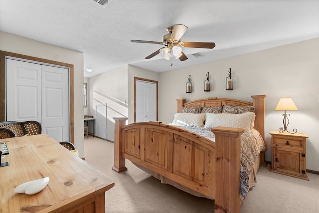 bedroom with ceiling fan, light colored carpet, and a textured ceiling