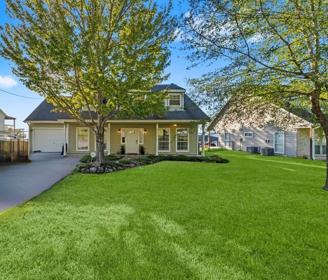 view of front of home with central AC, a porch, a garage, and a front lawn