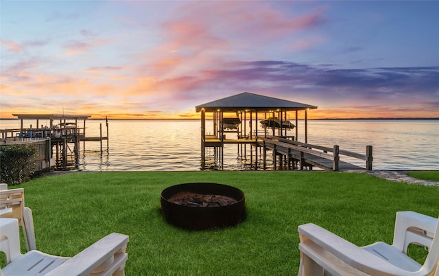 dock area featuring a fire pit, a water view, and a yard