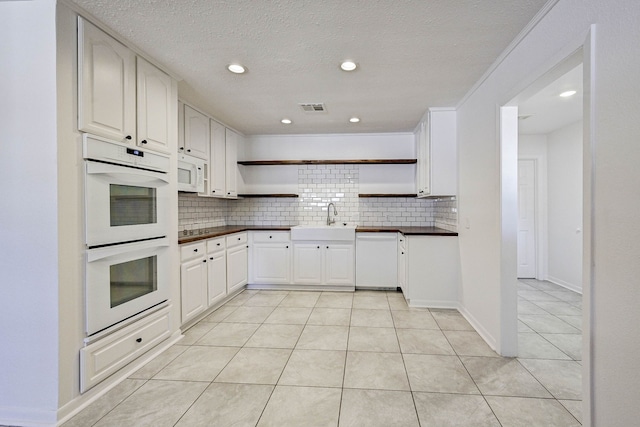 kitchen with white cabinetry, sink, backsplash, white appliances, and light tile patterned floors