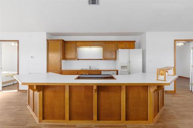 kitchen featuring white refrigerator with ice dispenser, black electric stovetop, light hardwood / wood-style floors, and sink