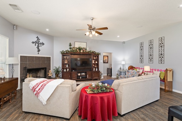 living room featuring dark hardwood / wood-style floors, ceiling fan, and a tile fireplace